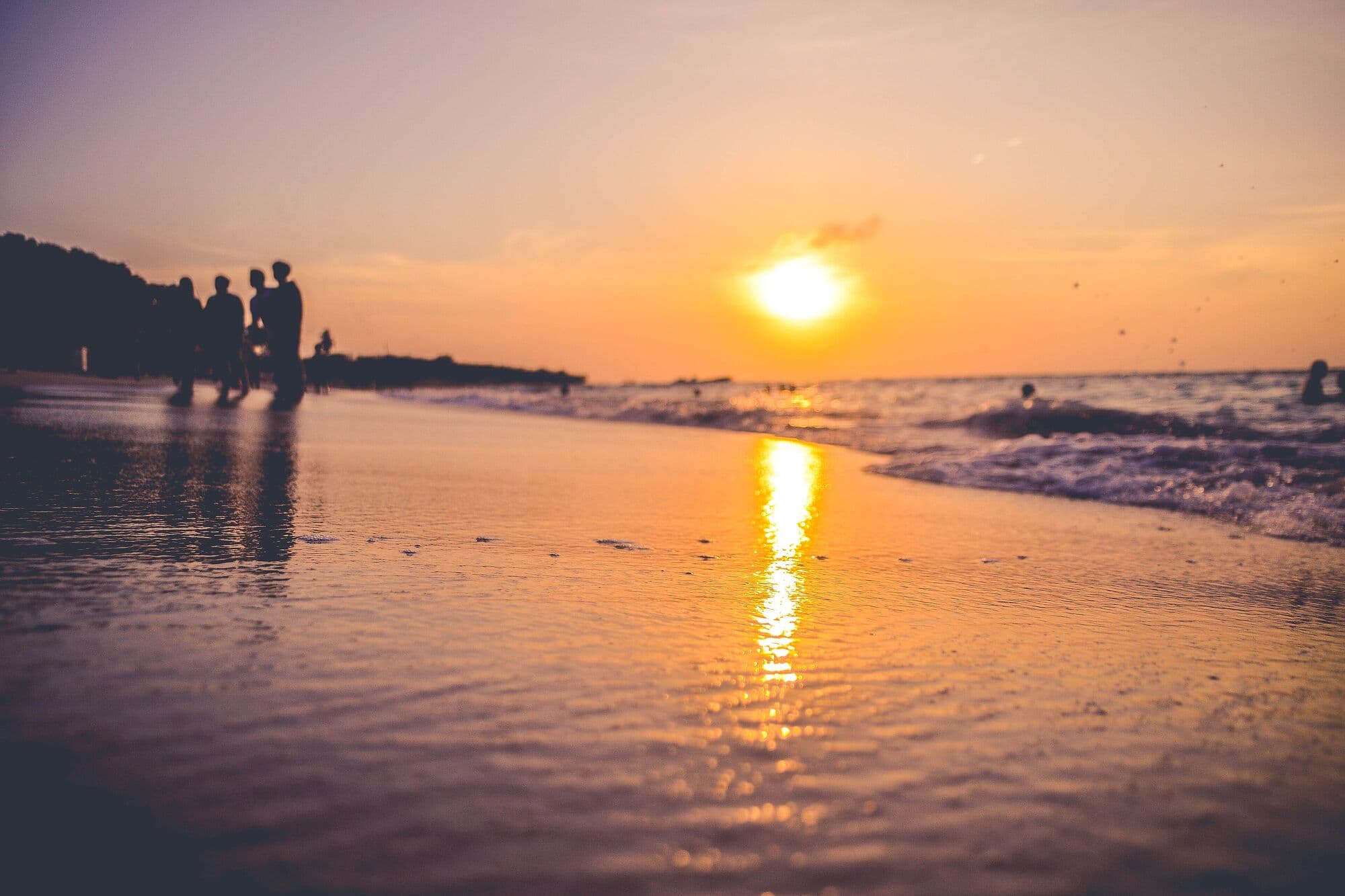 Friends at the water's edge on Playa Blanca, Barú, as the sun sets over the Caribbean