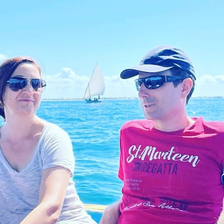 Two of us on a boat, with a dhow sailing behind on turquoise water