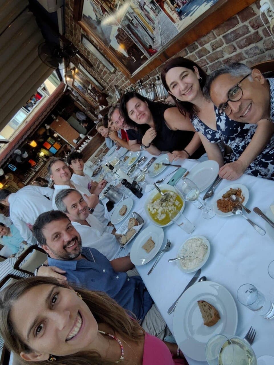 A long lunch table selfie, everyone leaning in